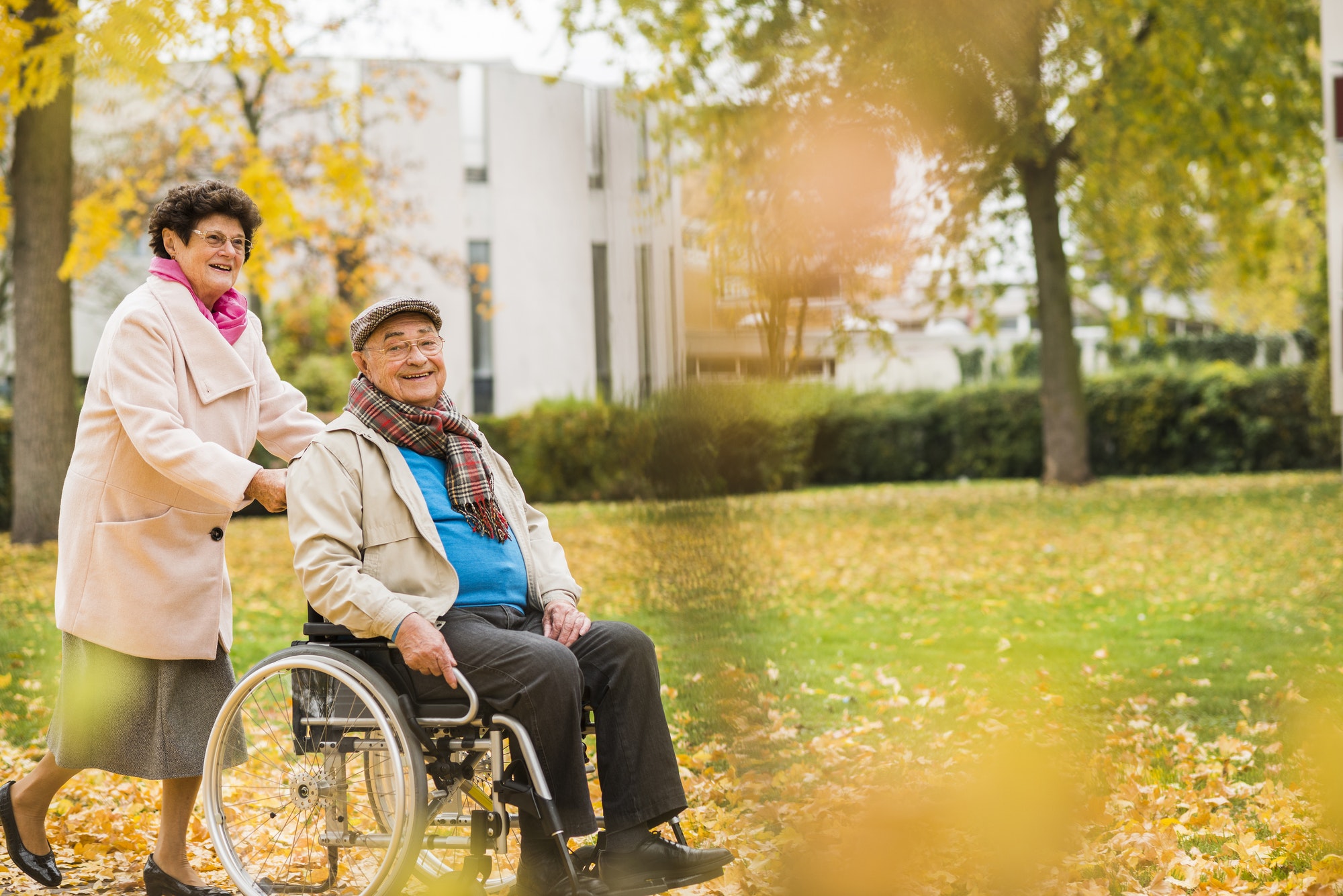 Senior woman pushing husband in wheelchair